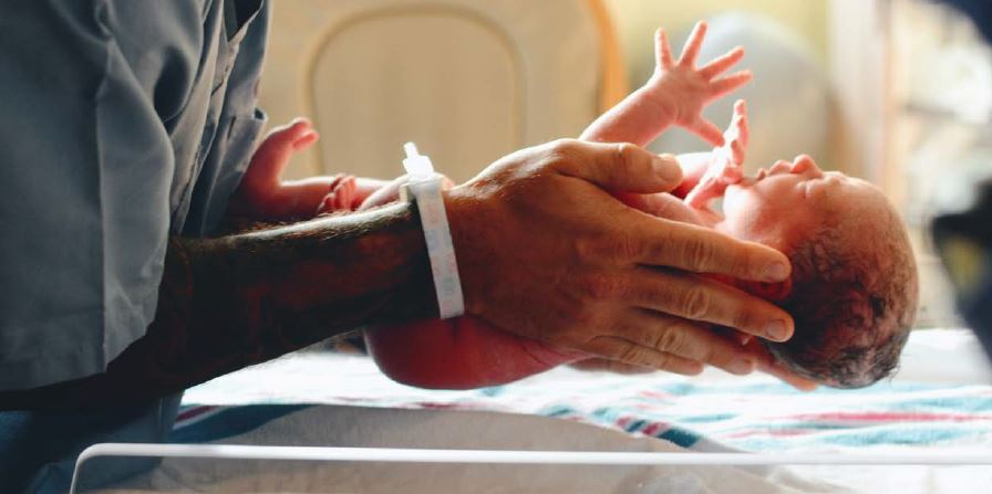 de hand van een zorgprofessional houden een pas geboren baby vast - de geboortezorg Zoetermeer gaat veranderen door mogelkijke sluiting van de acute geboortezorg
