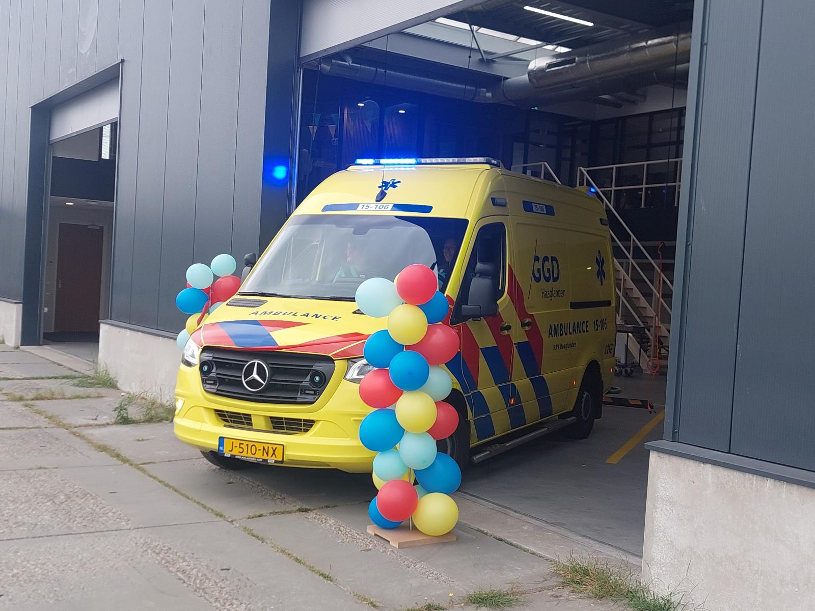 Een ambulance met daarin wethouder Mariëlle Vavier en ambulancechauffeur Kimberly rijdt op 4 september 2024 door een rood lint om de opkomstlocatie Harnasch in Harnaschpolder, Den Hoorn officieel in te wijden.