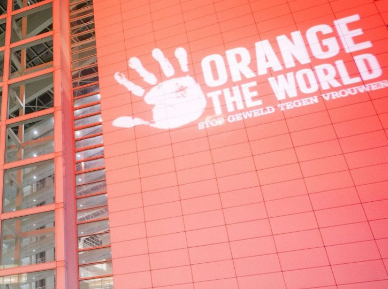 Rood/oranje muur met witte letters: Orange the world stop geweld tegen vrouwen.