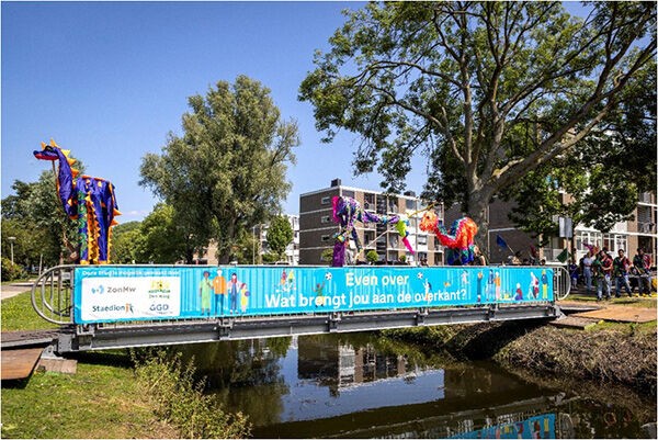 Brug over water in een woonwijk met vrolijke optocht van mensen en kleurige versieringen